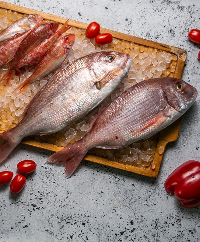 Δύο ολόκληρα ψάρια πάνω σε τριμμένο πάγο με ντοματίνια
